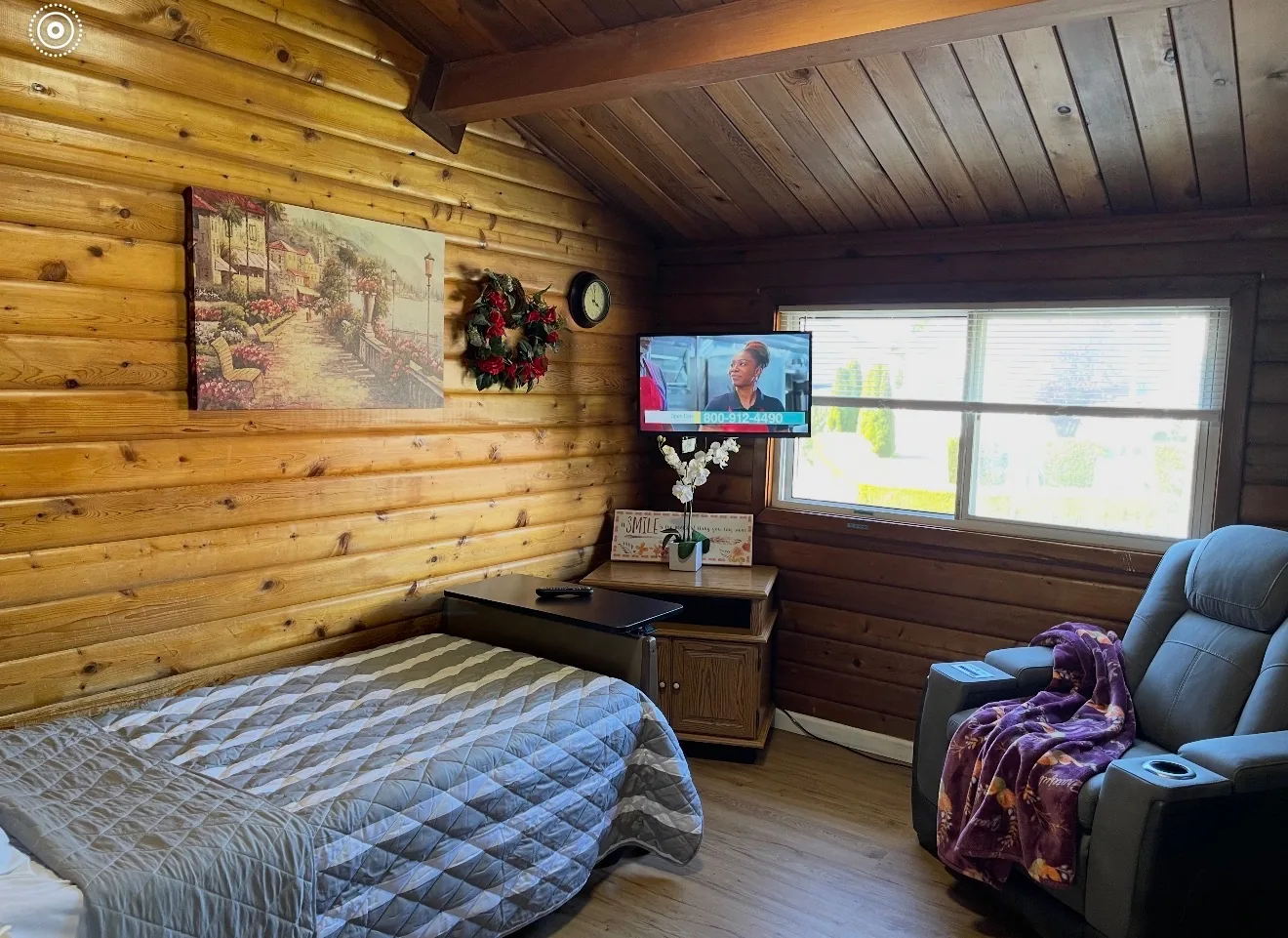 A resident bedroom at Birdsong Adult Family Home in Kent, with a recliner, artwork and a window onto the garden