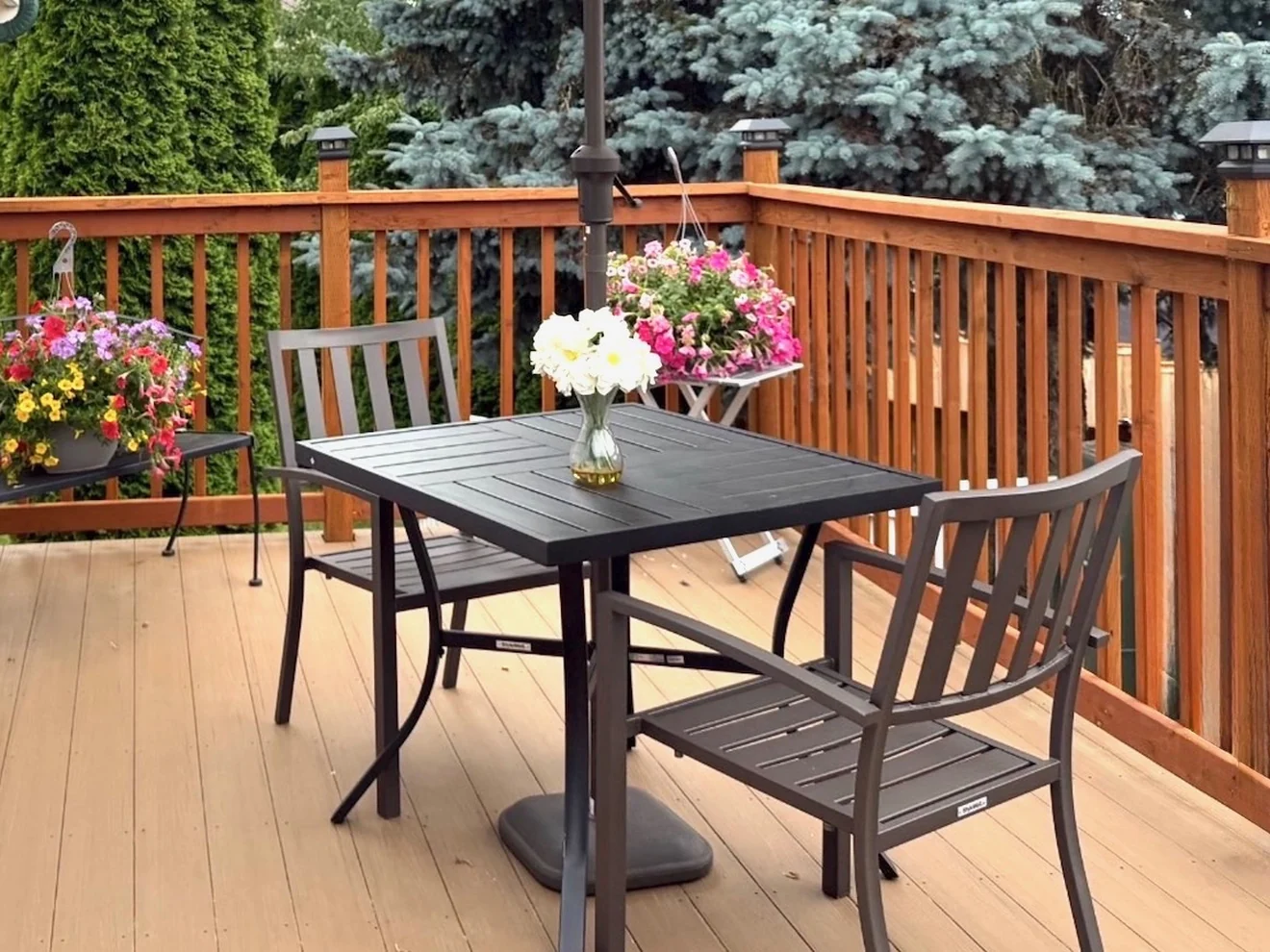 The back deck at Birdsong Adult Family Home, with a table, chairs and hanging flower baskets